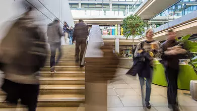 blurred image of people going up a stairwell and another couple of people walking towards the camera to the side of the stairs