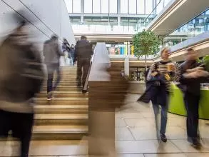 blurred image of people going up a stairwell and another couple of people walking towards the camera to the side of the stairs
